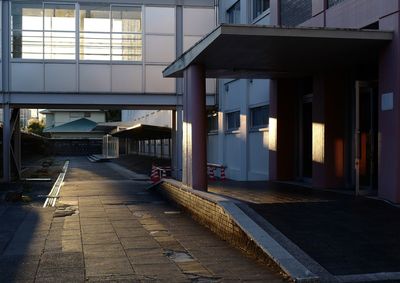 Empty footpath amidst buildings in city