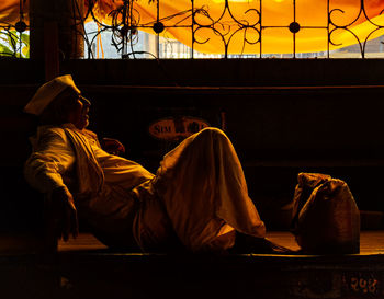 Rear view of couple sitting on floor at sunset