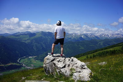 Rear view of man standing on rock against mountain