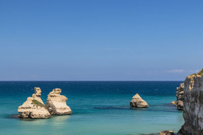 Rocks in sea against blue sky