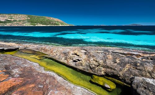 Scenic view of rocks on beach against blue sky