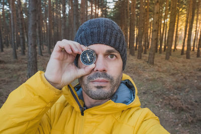 A man holds a compass over his right eye in nature. concept of searching and orientation