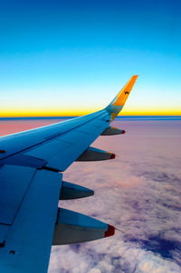 Close-up of airplane wing against cloudy sky
