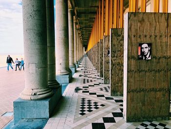 Rear view of people walking on footpath by building