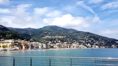 Aerial view of townscape by sea against sky