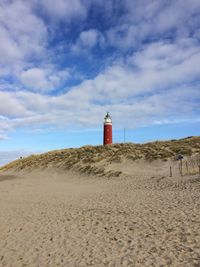 Lighthouse on beach against sky