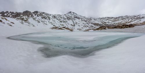 Scenic view of lago della vacca and snow covered mountains