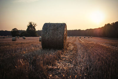 Hay bales on field against sky during sunset