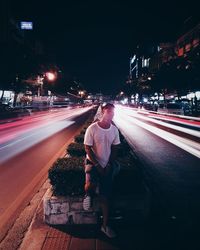 Young man looking at light trails on road in city