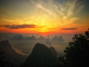 Scenic view of silhouette mountains against orange sky