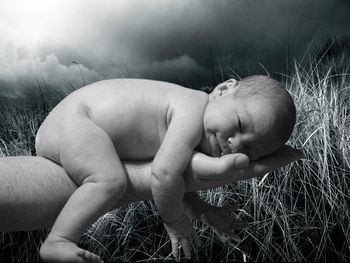 Cropped image of person carrying baby over grass