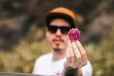 A young man holding a prickly pear