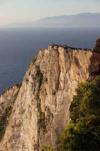 Scenic view of rocky mountain by sea against sky