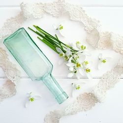 Close-up of white flowers and empty bottle on table