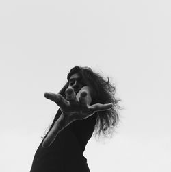 Low angle view portrait of young woman gesturing against gray background