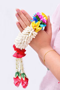 Low section of woman holding multi colored flowers against white background