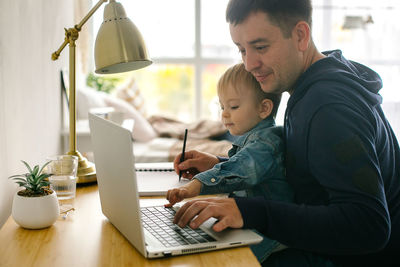 Side view of man using laptop at home