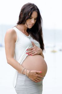 Beautiful pregnant woman standing at beach