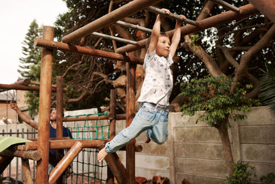 Low angle view of boy hanging at park