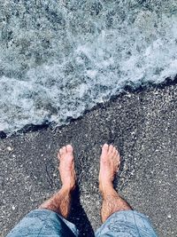 Low section of man standing on shore