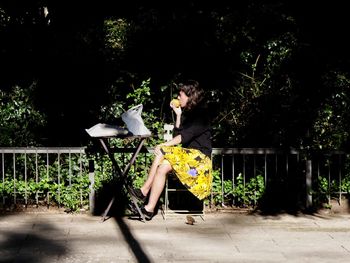 Woman sitting on chair against plants