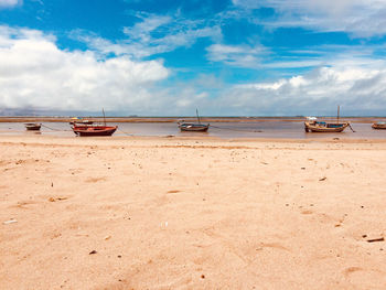 Boats moored on beach against sky