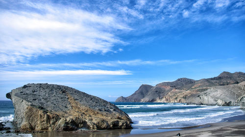 Scenic view of rocks by sea against sky