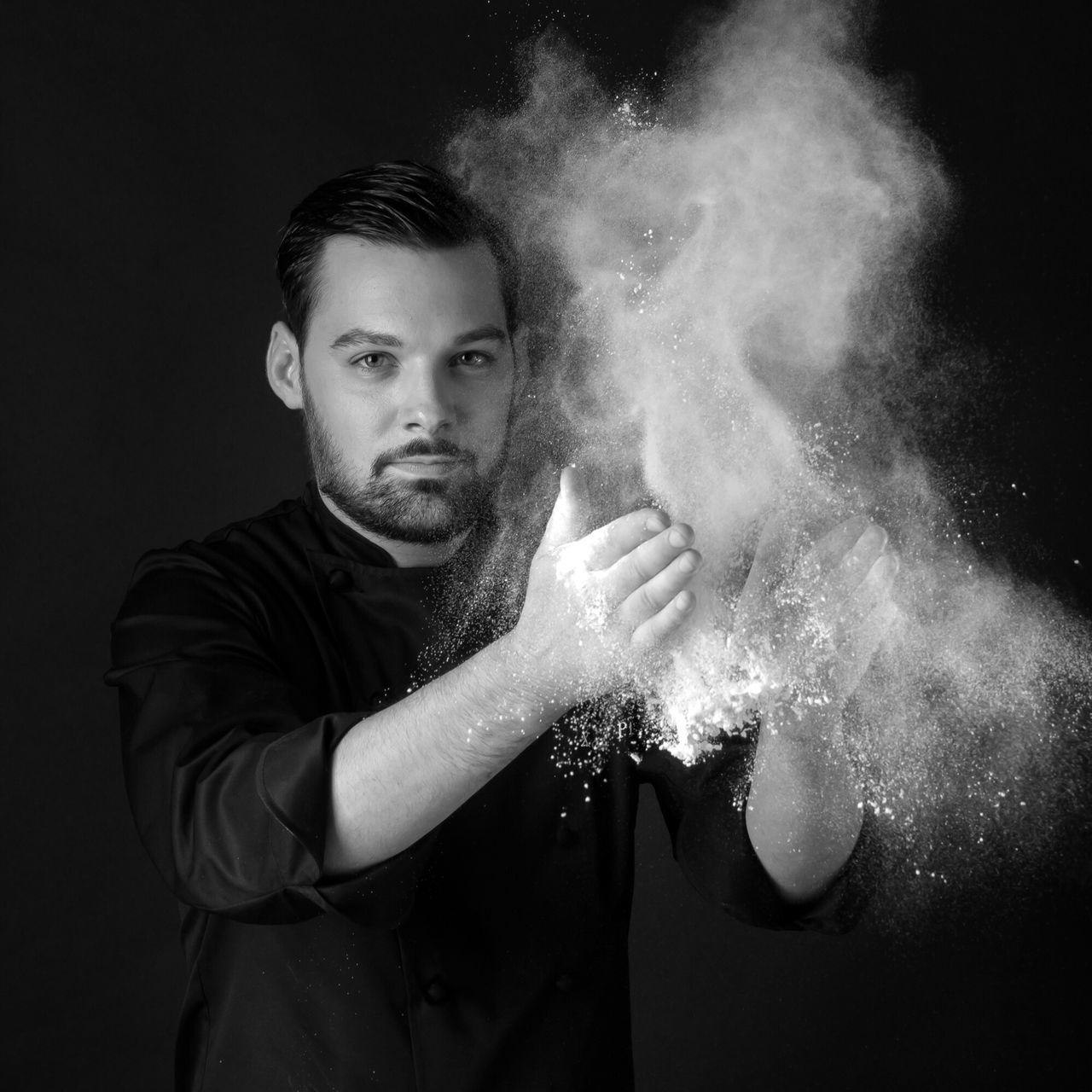 studio shot, black background, looking at camera, real people, portrait, one person, young adult, motion, front view, young men, lifestyles, exercising, men, human hand, muscular build, indoors, talcum powder, one man only, only men, close-up, adult, people