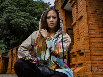 Portrait of young woman standing against wall