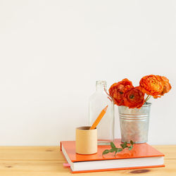 Red roses in vase on table against wall