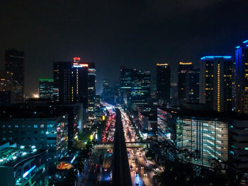 High angle view of illuminated street amidst buildings in city at night