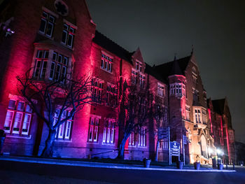 Illuminated building by street at night