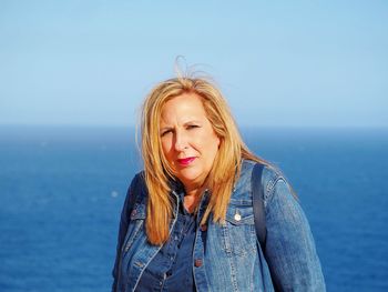 Portrait of beautiful young woman against sea