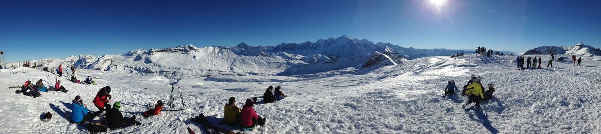 Panoramic view of people on snow covered landscape against sky