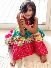 Portrait of cute girl gesturing while sitting on floor at home