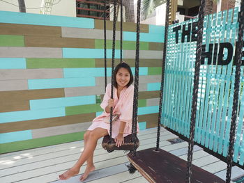 Portrait of a smiling young woman sitting on swimming pool