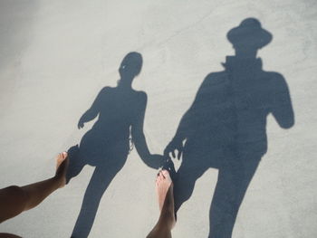 Low section of couple with shadow at beach