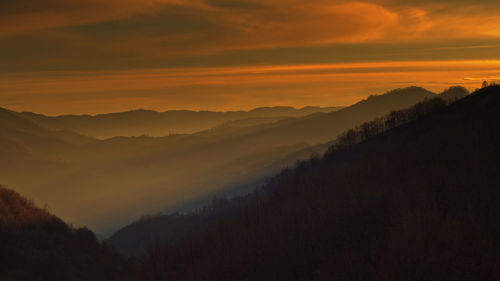 Scenic view of silhouette mountains against orange sky