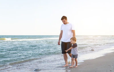 Full length of father and daughter standing on beach