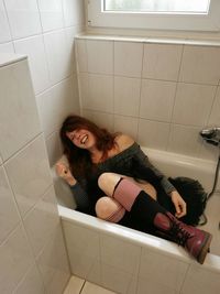High angle portrait of young woman sitting on floor at home