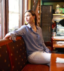 Young woman looking away while sitting on sofa