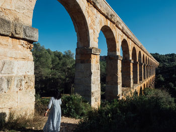 Woman standing against arch bridge