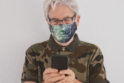 Man in mask using mobile phone against white background