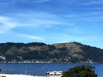 Scenic view of sea and mountains against blue sky