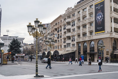 People walking on street against buildings in city