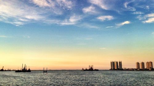 Boats in sea at sunset