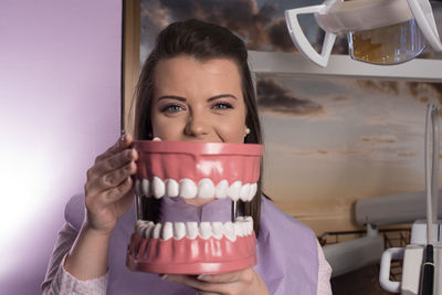 Portrait of young woman holding anatomical model of teeth