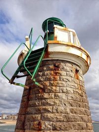 Low angle view of old light house against cloudy sky