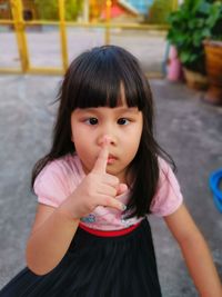 Portrait of cute girl with finger on lips standing on land