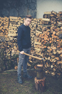 Portrait of teenage boy cutting log